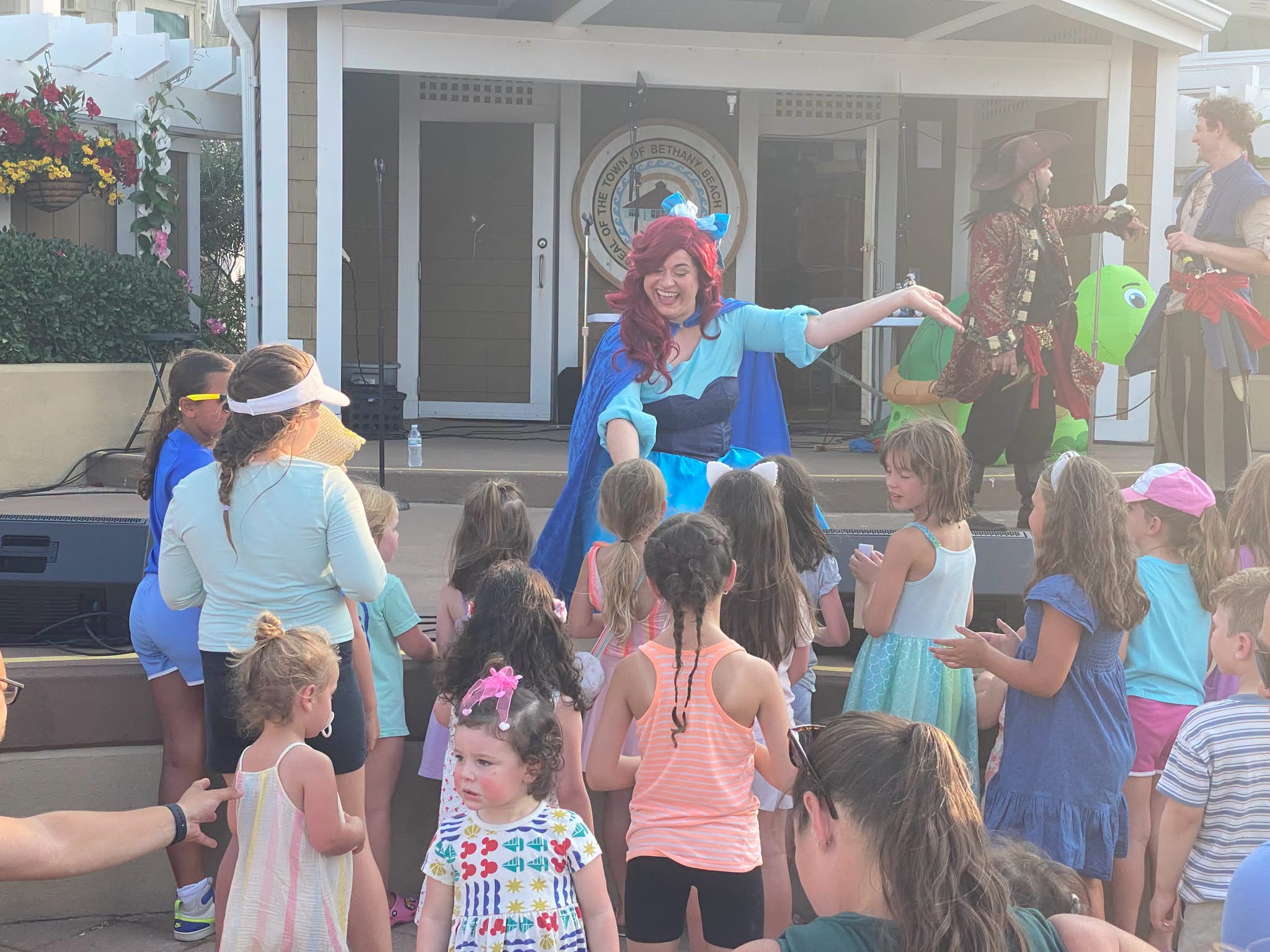 A costumed singer inviting children to join in at the front of the stage