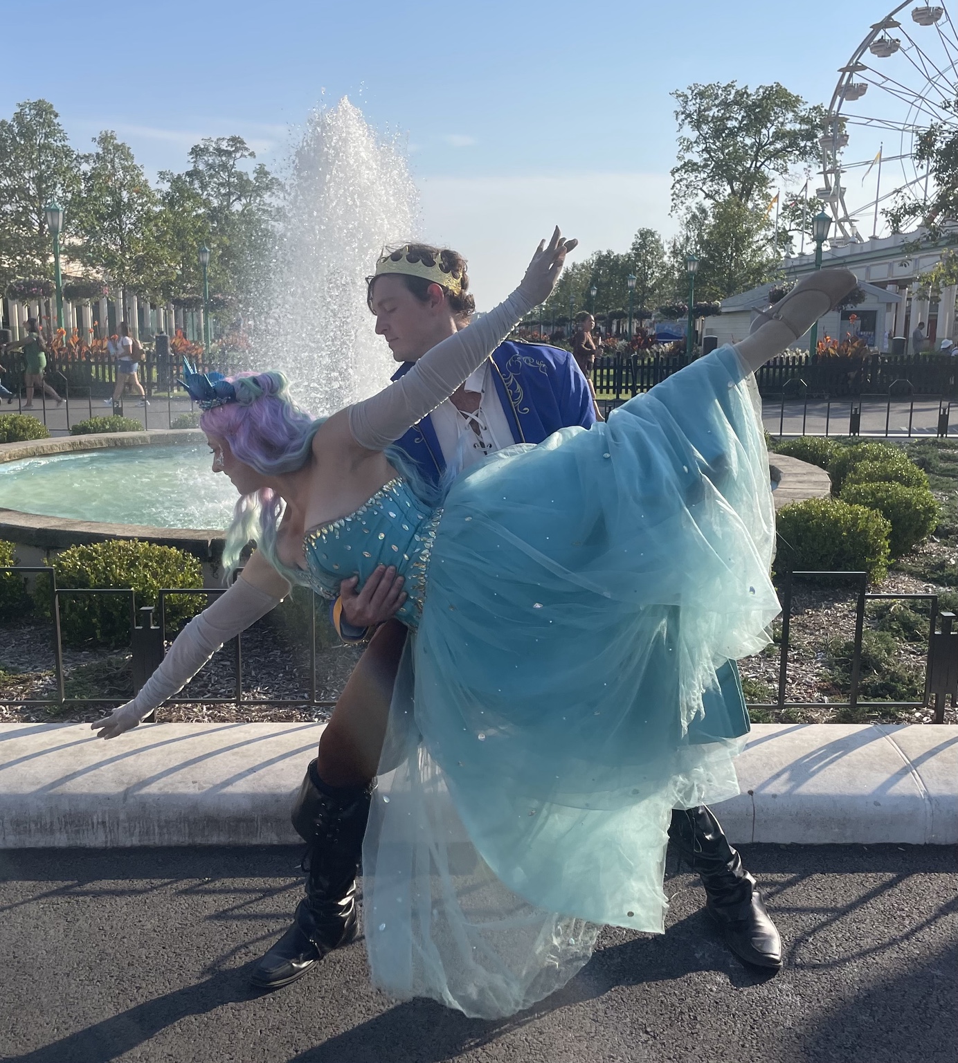 A princess and prince striking a dance pose beside a fountain