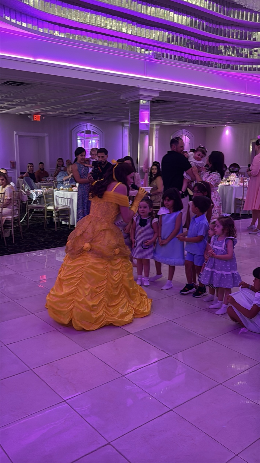Belle in a yellow gown greeting children at an event